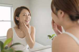 朝の洗面所で肌の状態を観察する女性