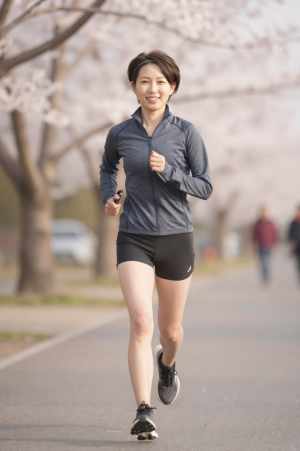 桜並木をジョギングする女性