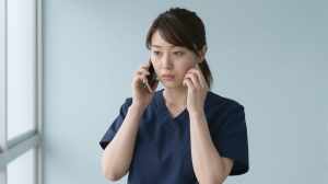 廊下で電話をする看護師