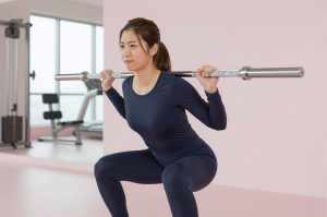 ジムで集中してスクワットする女性