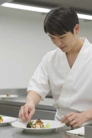 厨房で料理を盛り付けるシェフ