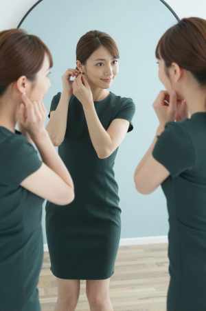 鏡でイヤリングを調整する女性