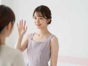 笑顔で手を振る女性のパステルカラードレスポートレート