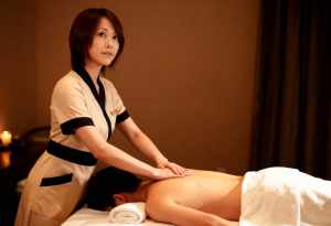 スパのマッサージ テーブルに横たわっている男性にマッサージを施す女性を正面カメラ ア...。