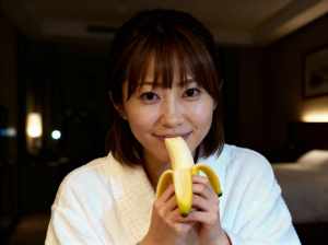 薄暗い部屋でバナナを食べる若い女性をクローズアップ カメラ アングルから写実的に撮影...。