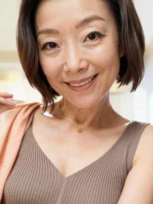 短く濃い茶色の髪と茶色の目をした中年のアジア人女性がカメラに向かって微笑んでいるクロ...。