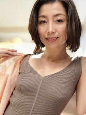 濃い茶色の短い髪で、V ネックのリブ編みのノースリーブの明るい茶色のトップスを着て、...。