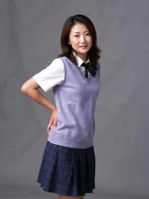 無地のグレーの背景に自信を持ってポーズをとる学生服を着た若い女性を、全身カメラ アン...。