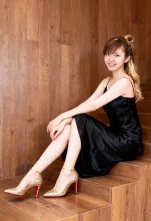 黒のサテンのスリップ ドレスとクリスチャン ルブタンの赤いヒールを履いて木製の階段に...。