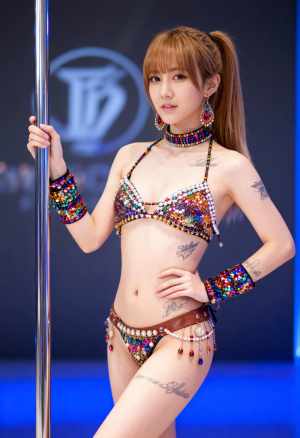 カラフルなスパンコールのついたビキニを着てポールの横で自信を持ってポーズをとる若い女...。