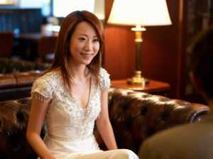 豪華なホテルのロビーで茶色の革張りのソファに座っている若いアジア人女性のポートレート。