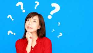 明るい青色の背景に疑問符で囲まれた、思慮深い表情を持つ若いアジア人女性のポートレート。