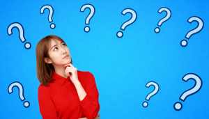 赤いシャツを着た長い茶色の髪の若い女性が、あごを手に当てて画像の中央に立って、思慮深...。