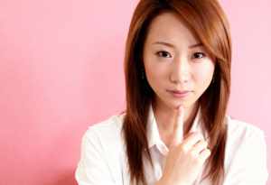 白い襟付きのシャツを着た、赤茶色の長くまっすぐな髪を持つ若いアジア人女性のポートレート。