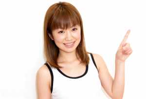 人差し指を上に向け、明るい表情をした若い女性。