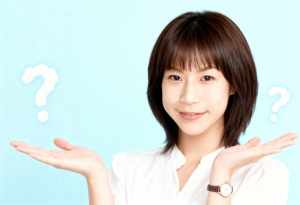 ショートボブのヘアカットをした若いアジア人女性が、両手で何かを差し出しながら視聴者に...。