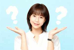 画像の中央に立っている、短いストレートのダークブラウンのボブヘアと前髪を持つアジア系...。