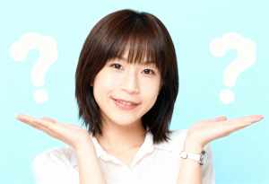 短くストレートなダークブラウンのボブヘアカットと白い肌を持ち、カメラに向かって微笑む...。