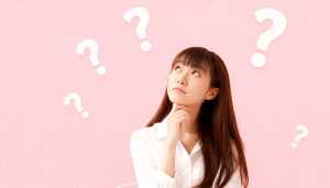 白いブラウスを着た長い茶色の髪の若い女性が、画像の中央に顎を乗せて座り、思慮深い表情...。