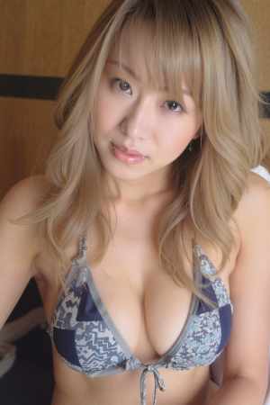 青と白の模様のビキニトップを着た、ウェーブのかかったブロンドの長い髪を持つ若い女性を...。