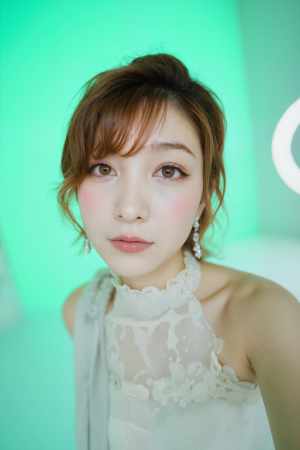 柔らかな光を当てた緑の背景に、薄手の白いドレスと揺れるイヤリングを身に着けた、柔らか...。