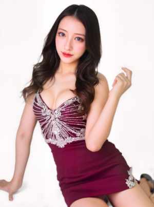 ブルゴーニュの短いドレスを着てエレガントにポーズをとる若い女性を、正面カメラのアング...。