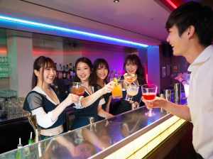 バーの後ろに立っている 5 人の若いアジア人女性のグループが、それぞれ異なる色のカク...。