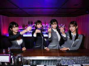 ビジネス服を着た 4 人の若い女性がバーカウンターの後ろに立ち、手にマティーニ グラ...。