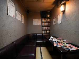 薄暗く、居心地の良い雰囲気のお部屋で、コーナーブースと新聞を敷いたテーブルが特徴です。