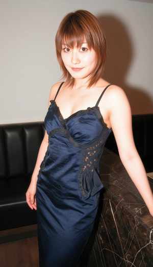 薄暗い部屋で黒い革張りのソファに向かって自信を持ってポーズをとる若い女性をポートレー...。