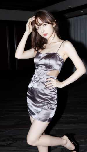 絹のような銀色のドレスを着て自信を持ってポーズをとる若い女性を横から見た写真のように...。