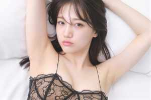 黒いレースのブラレットを着用し、腕を頭の上に上げてポーズをとる若い女性を、クローズア...。