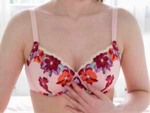ピンクの花柄のブラジャーを着けた女性の上半身を中心に正面からクローズアップしたショットです。