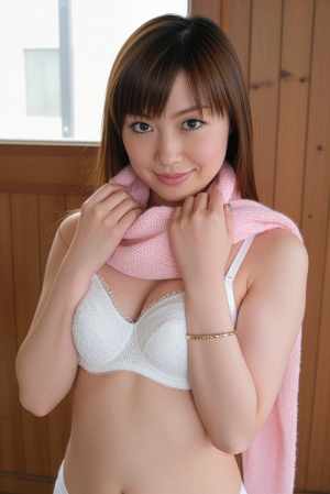 白いブラジャーとピンクのスカーフを身に着け、カジュアルな服装でポーズをとる若い女性を...。