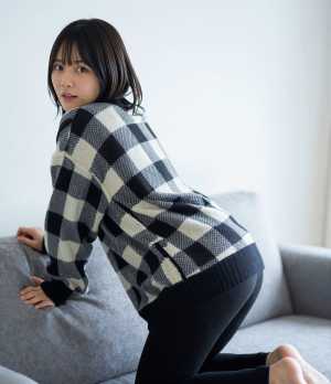 黒のセーター姿でソファに佇む女性