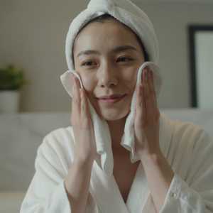 洗面所で洗顔後に顔を拭く女性