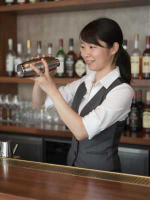 バーテンダーの女性がカクテルをシェイク