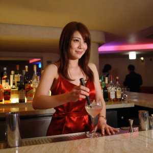 巨乳バーカウンターでカクテルを作る女性