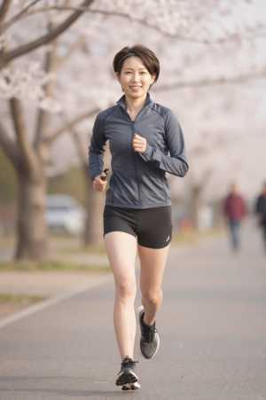桜並木をジョギングする女性