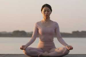 夕暮れの湖畔で瞑想する女性