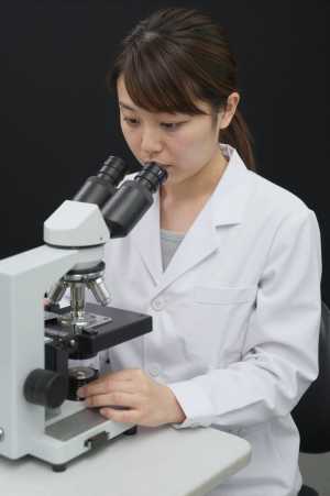 顕微鏡で作業する検査技師
