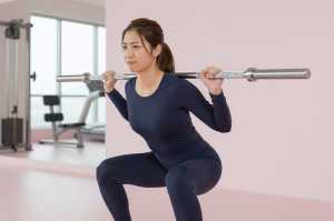 ジムで集中してスクワットする女性