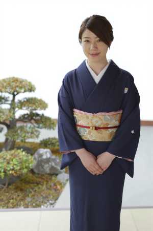 旅館の庭園で客を迎える女性