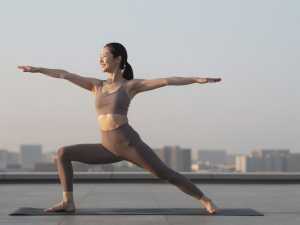 屋上ヨガで日の出を浴びる女性