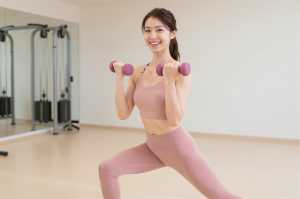 ジムでダンベルランジをする女性