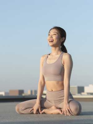 屋上ヨガで夕日を眺める女性