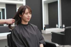 ヘアサロンで髪を梳かれる女性