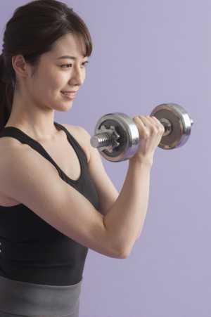 集中してダンベルカールをする男性