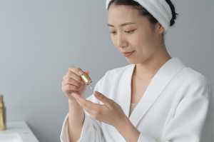 手のひらに美容オイルを垂らす女性