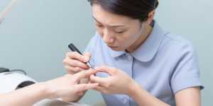 ジェルランプでトップコートを塗るネイリスト